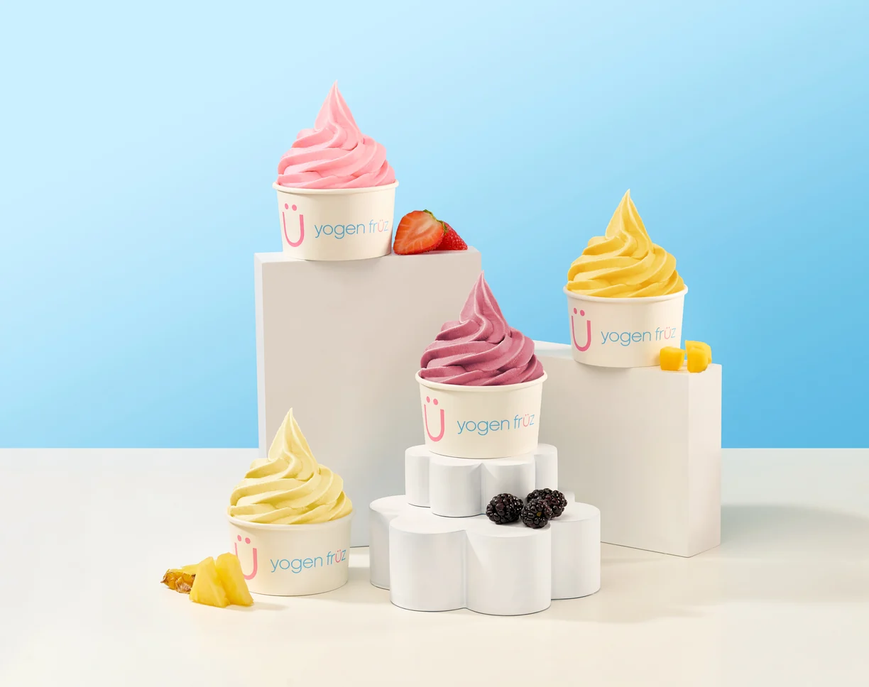 Four cups of Yogen Früz frozen yogurt in strawberry, mango, berry and pineapple flavours on white blocks
