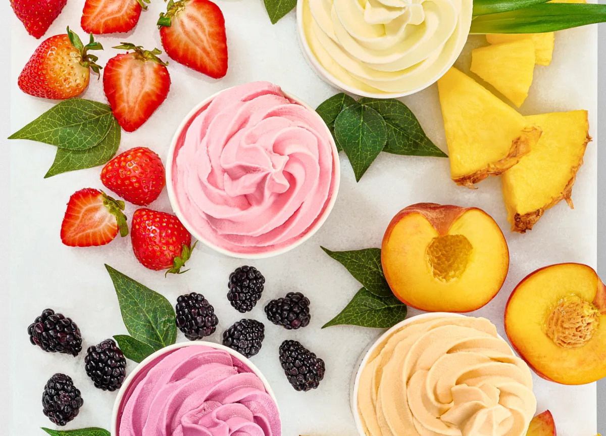 A tray of Yogen Früz frozen yogurt cups with fresh strawberries, blackberries, pineapple and peach
